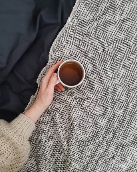 A cup of tea on a knit blanket
